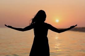download (10) mulher diante do amanhecer, com os braços abertos em sinal de libertação.