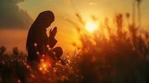 download (2) uma pessoa orando sozinha ao amanhecer, com o sol nascendo atrás, simbolizando intimidade e conexão com Deus.