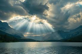 download (4) amanhecer visto de uma montanha, com raios de sol atravessando as nuvens, simbolizando renovo, fé e esperança.