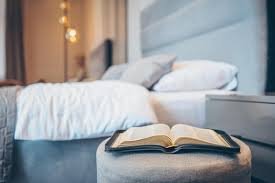 download (21) Cama com Bíblia aberta e iluminação quente, simbolizando devocional noturno.